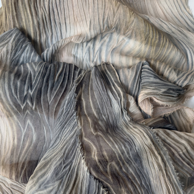 Close-up of a hand-painted Otta-Italy wool silk blend scarf showcasing soft shades of brown, gray, and beige with delicate hand-fringed edges.
