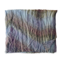 Colorful mix wool and silk scarf in light blue, purple, brown and green shades on a white background. It is hand-painted scarf in measures 193 x 54 cm by otta-italy scarves brand. Luxury Italian accessory, soft and warm scarf for women and men.
