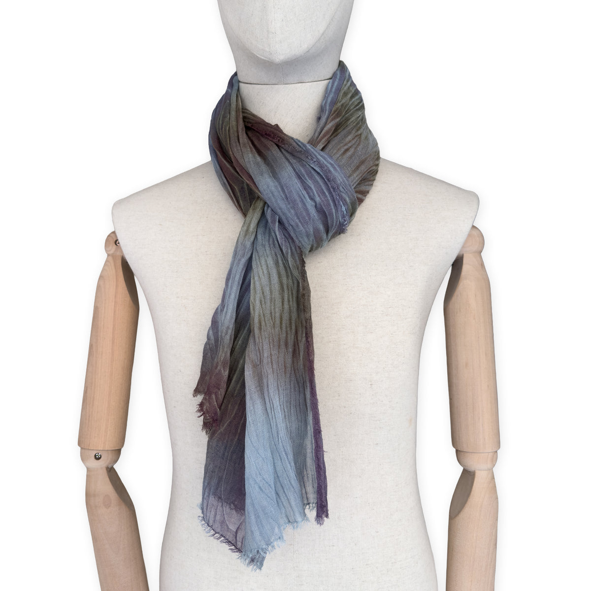 Mannequin wearing scarf on a white background. Hand-painted mix wool and silk scarf by Otta-Italy, 193 x 54 cm, featuring light blue, purple, brown and green colors. Luxury Italian accessory, soft and warm scarf for women and men.
