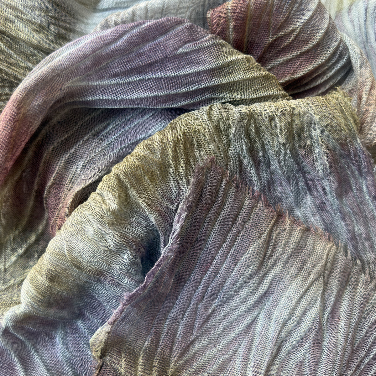 Close-up of soft fabric. Hand-painted mix wool and silk scarf by Otta-Italy, 193 x 54 cm, featuring light blue, purple, brown and green colors. Luxury Italian mix accessory, soft and warm scarf for women and men.

