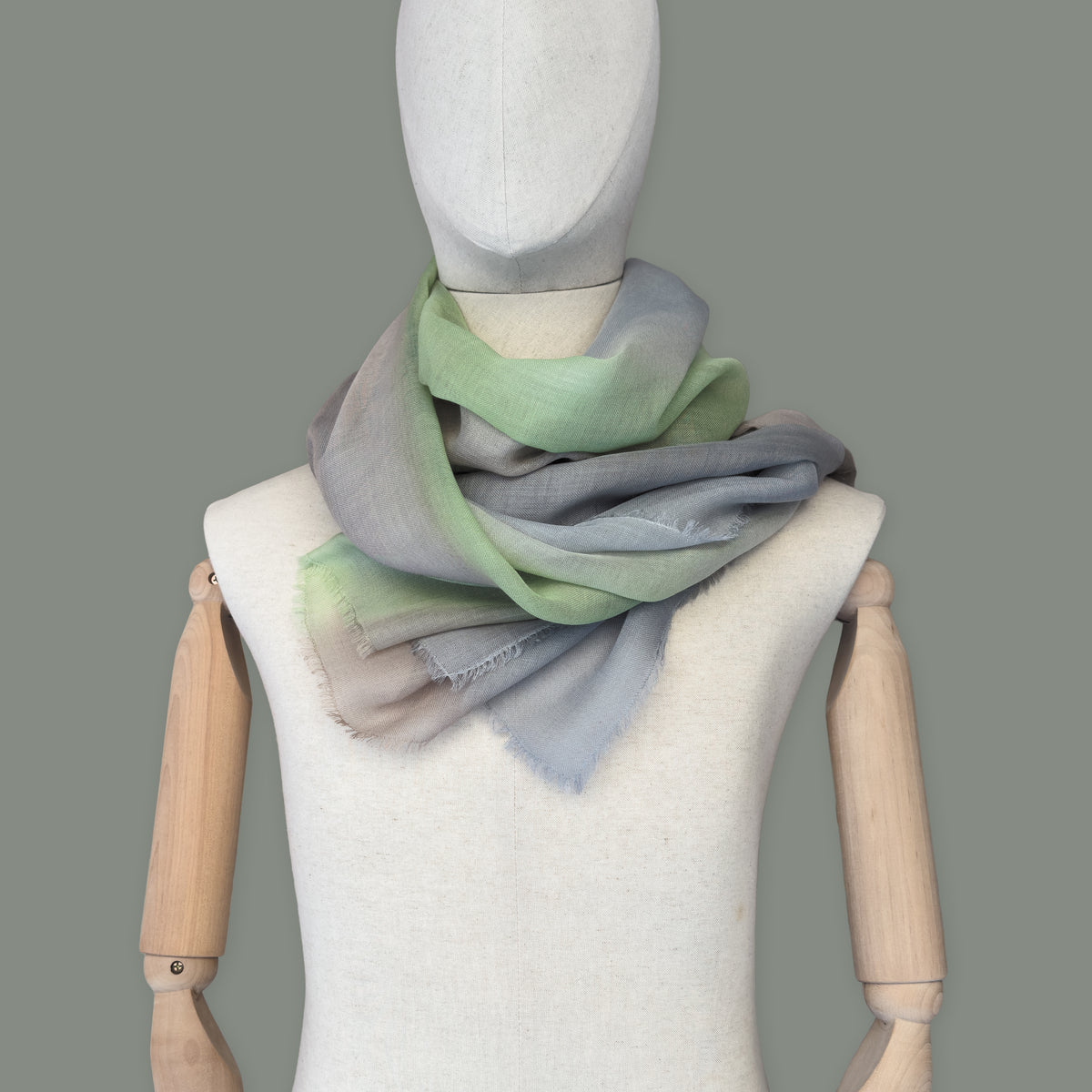 Mannequin wearing scarf on a gray background. Hand-painted wool & silk scarf by Otta-Italy, 70 x 197 cm, featuring 
brown, gray and light green. Luxury Italian wool & silk accessory, soft and warm scarf for women and men.
