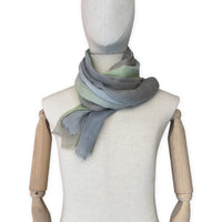 Mannequin wearing a hand-painted Otta wool & silk scarf on a white background in 
brown, gray and light green tones. Lightweight, warm, and elegant accessory measuring 70 x 197 cm. Unique artisan scarf with hand-fringed edges, perfect for women and men.
