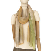 Mannequin wearing an elegant hand-painted Otta wool silk blend scarf on a white background. Warm green, orange and beige tones.
