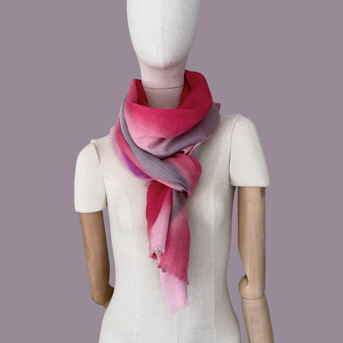 Mannequin wearing scarf on a gray background. Hand-painted wool & silk scarf by Otta-Italy, 52 x 165 cm, featuring 
red, pink, and gray. Luxury Italian wool & silk accessory, soft and warm scarf for women and men.
